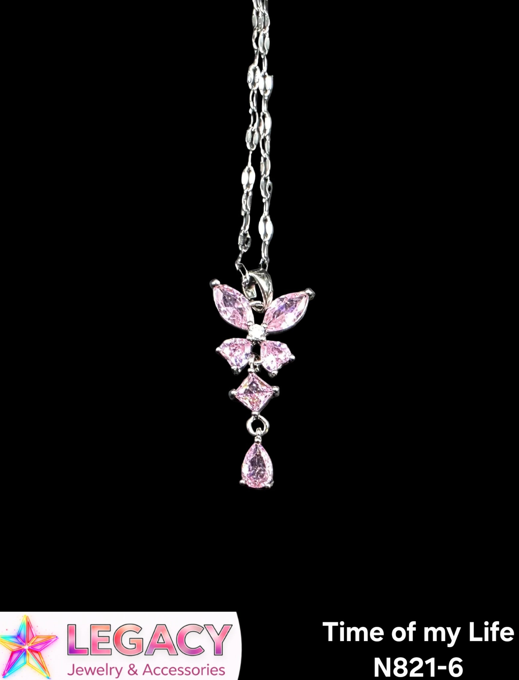 A silver-toned pendant necklace featuring a butterfly and floral design with pink gemstones, shown against a solid black background. A white banner at the bottom left displays the 'Legacy Jewelry & Accessories' logo, and text at the bottom right reads 'Time of my Life N821-6'.