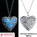 A heart-shaped filigree pendant necklace shown in a split comparison: on the left, glowing blue in the dark, and on the right, silver in the light. The image features the 'Legacy Jewelry & Accessories' logo in the bottom-left corner and the text 'My Heart will Glow On N805-6' in the bottom-right.
