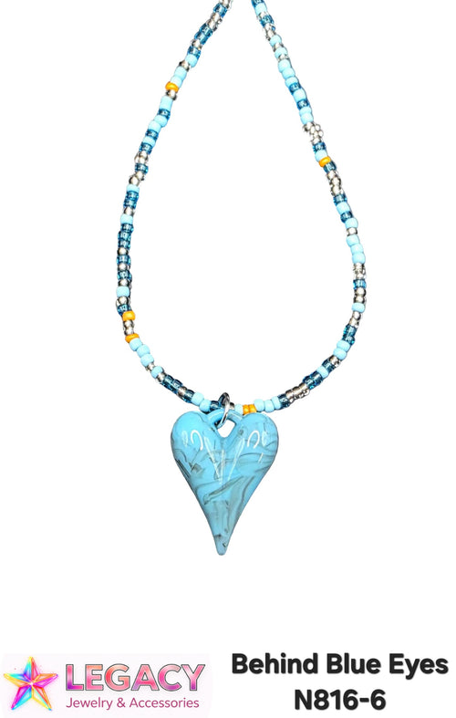 A beaded necklace with a light blue heart-shaped pendant, featuring light blue, white, and yellow beads, shown against a white background with a Legacy Jewelry & Accessories logo and product code text at the bottom.